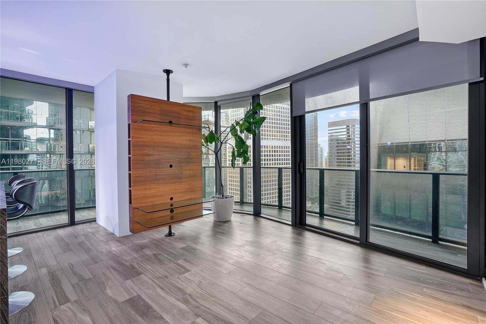 A modern living room features wood-look flooring, a rotating media console, and floor-to-ceiling windows — 801 S Miami Ave # 2805, Miami FL 33130, MIAMI, FL