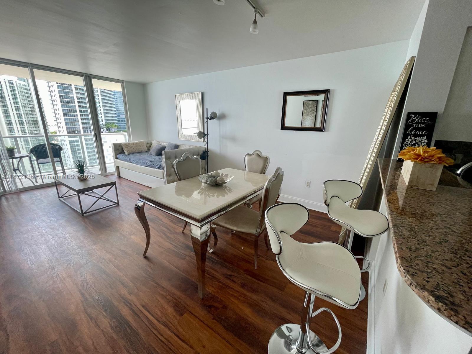 A dining area and living space feature wood floors, a glass-topped table, and balcony views — 1155 Brickell Bay Dr # 1805, Miami FL 33131, MIAMI, FL