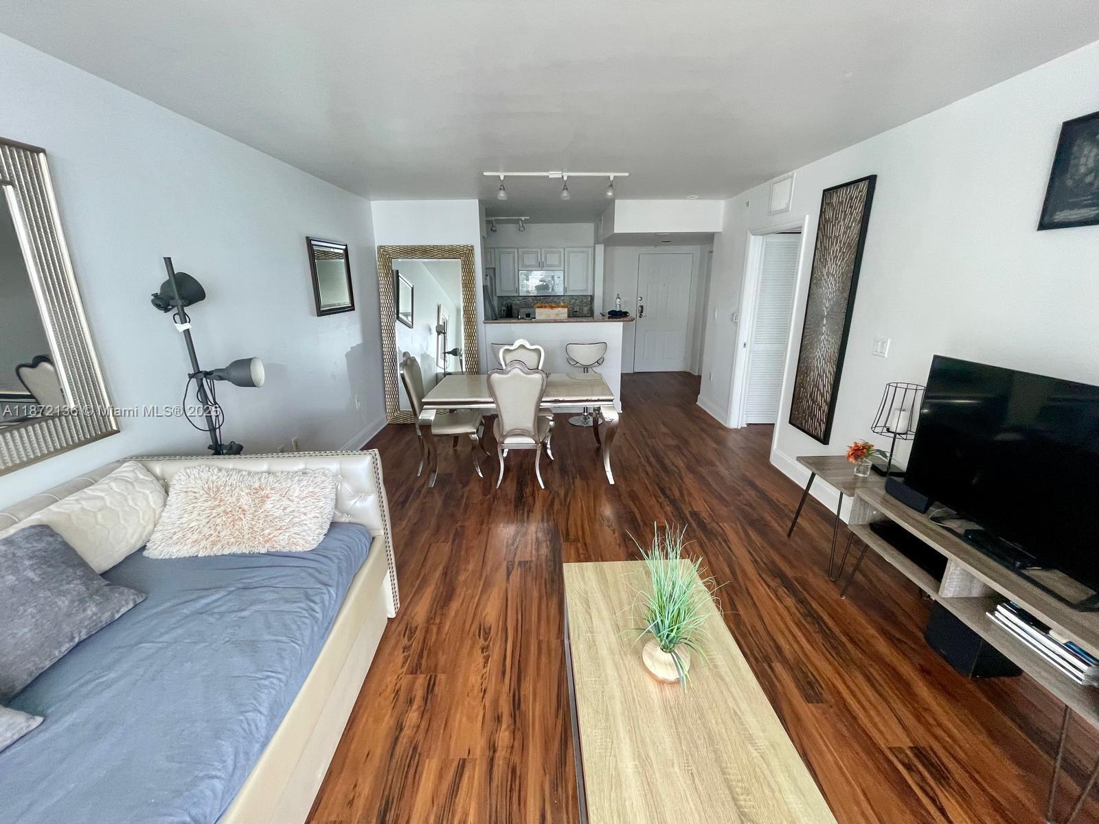 A living room and dining area feature wood-look flooring, a sofa, and a television console — 1155 Brickell Bay Dr # 1805, Miami FL 33131, MIAMI, FL