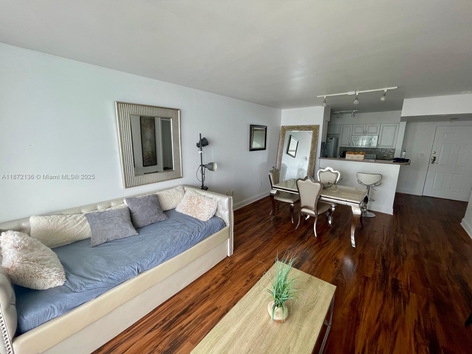 A living and dining area features wood flooring, a daybed, and an open kitchen — 1155 Brickell Bay Dr # 1805, Miami FL 33131, MIAMI, FL