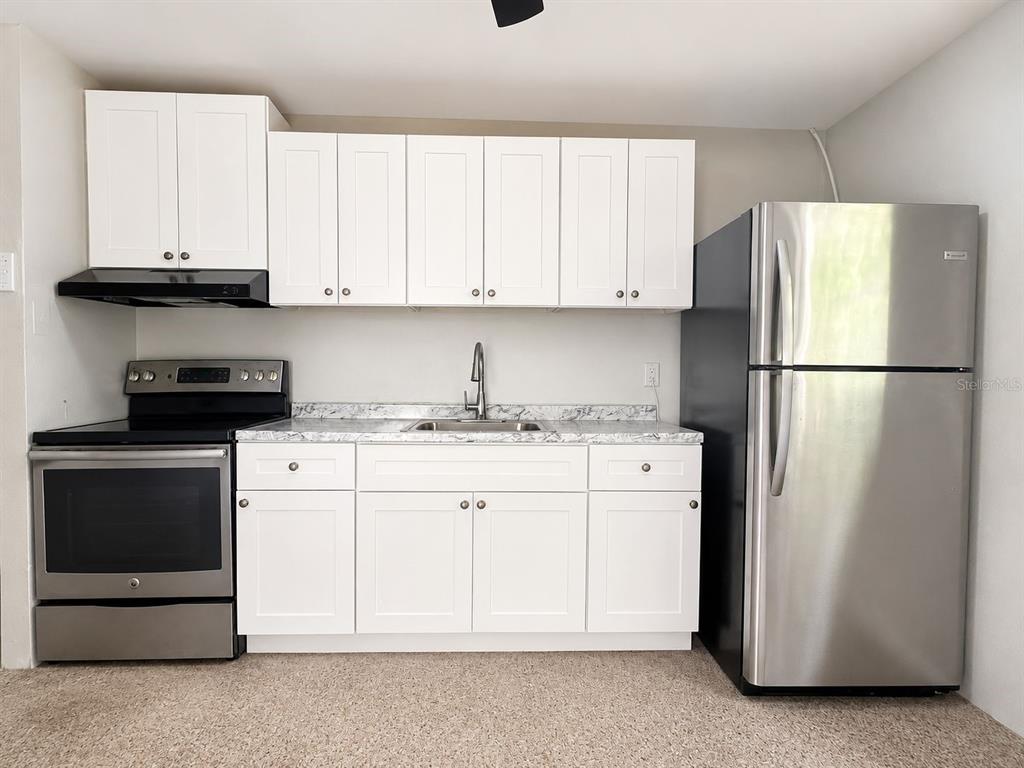 A kitchen features white cabinetry, stainless steel appliances, and a marble-patterned countertop — 38401 FERGUSON AVE, DADE CITY, FL