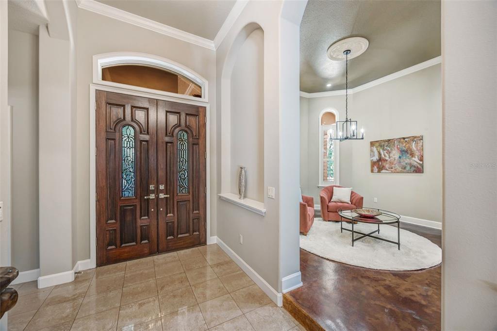 A foyer with tile floors leads into a living area featuring a chandelier and rug — 7519 YARDLEY WAY, TAMPA, FL