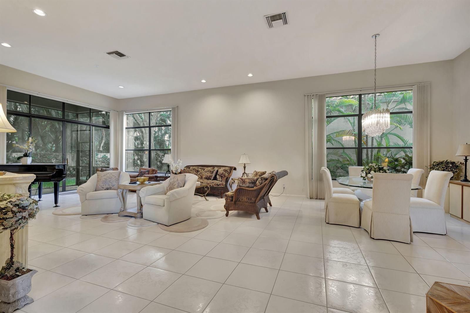 A spacious living and dining room with tile floors, large windows, and a grand piano — 4528 Barclay Fair Way, Lake Worth FL 33449, LAKE WORTH, FL