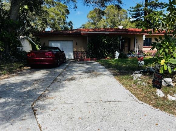 A red convertible is parked in the driveway of a single-story house with a red roof — 1942 ALTON DRIVE, CLEARWATER, FL
