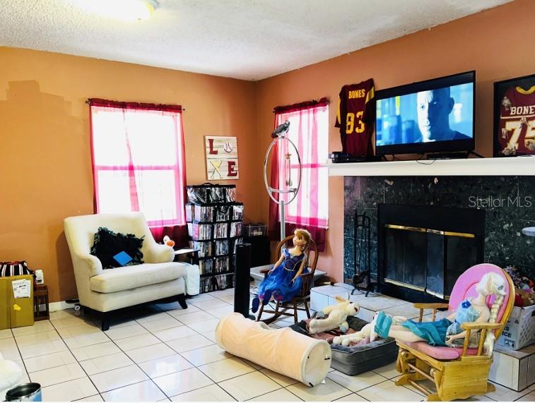 A living room features a fireplace, a television, a white armchair, and children's toys — 1942 ALTON DRIVE, CLEARWATER, FL