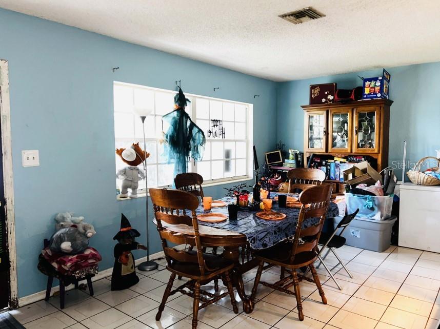 A dining room with light blue walls, tile flooring, a wooden table, and Halloween decorations — 1942 ALTON DRIVE, CLEARWATER, FL