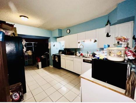 A kitchen with white cabinets, tiled floors, and a black refrigerator and microwave — 1942 ALTON DRIVE, CLEARWATER, FL