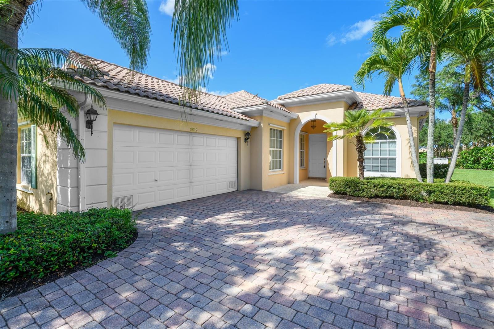 A single-story house with a yellow stucco exterior, tile roof, and a paved driveway — 8019 Nevis Place, Wellington FL 33414, WELLINGTON, FL