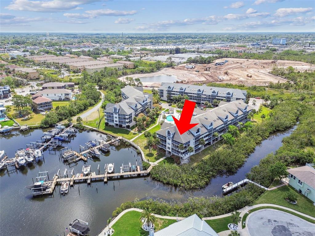 An aerial view shows a multi-story waterfront condominium building with a marina and boat slips — 5537 SEA FOREST DRIVE UNIT 301, NEW PORT RICHEY, FL