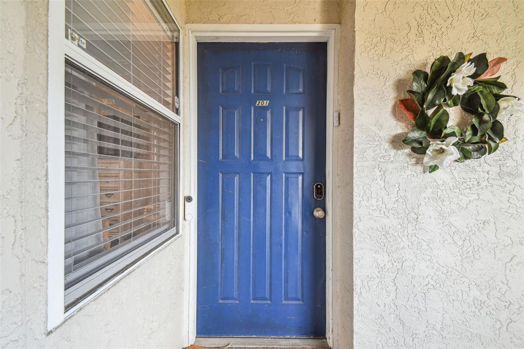 A blue front door with the number 301 is flanked by a window and wreath — 5537 SEA FOREST DRIVE UNIT 301, NEW PORT RICHEY, FL