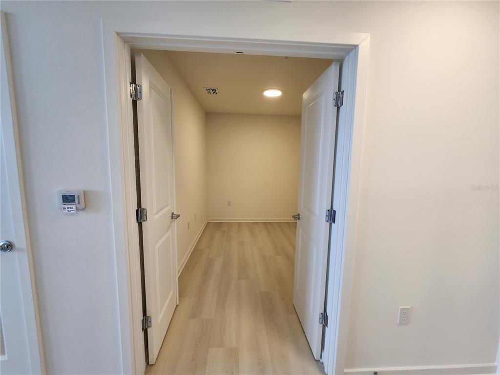 A view through an open doorway into a small, empty room with light wood-look flooring — 5579 MILLENIA PARK BLVD UNIT 509, ORLANDO, FL