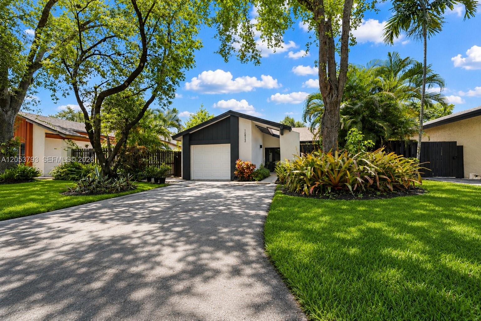A single-story house with a white garage, dark trim, and a paved driveway — 10932 SW 135th Ct Cir, Miami FL 33186, MIAMI, FL
