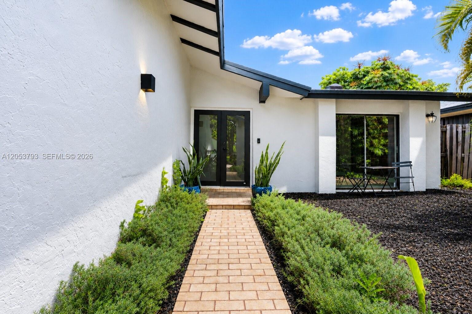 A brick walkway leads to the black-framed double front doors of a white stucco house — 10932 SW 135th Ct Cir, Miami FL 33186, MIAMI, FL