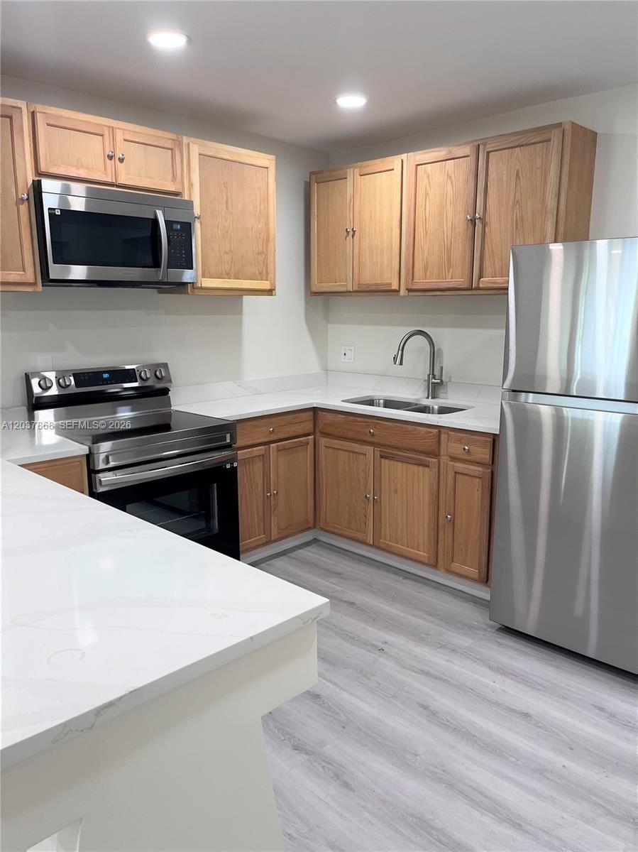 A kitchen features light wood cabinets, stainless steel appliances, and white quartz countertops — 2434 Polk St, Hollywood FL 33020, HOLLYWOOD, FL