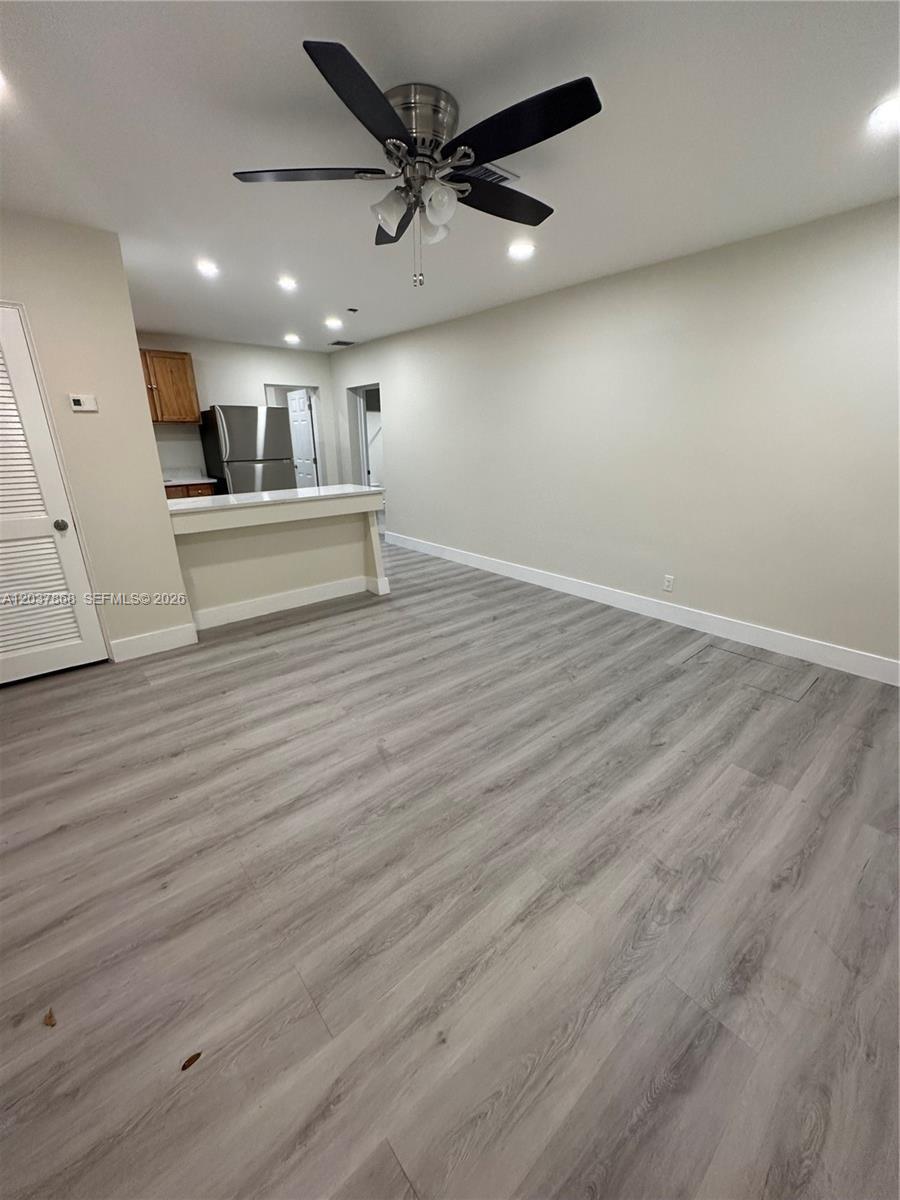 An open living area features light wood-look flooring, a ceiling fan, and a kitchen pass-through — 2434 Polk St, Hollywood FL 33020, HOLLYWOOD, FL