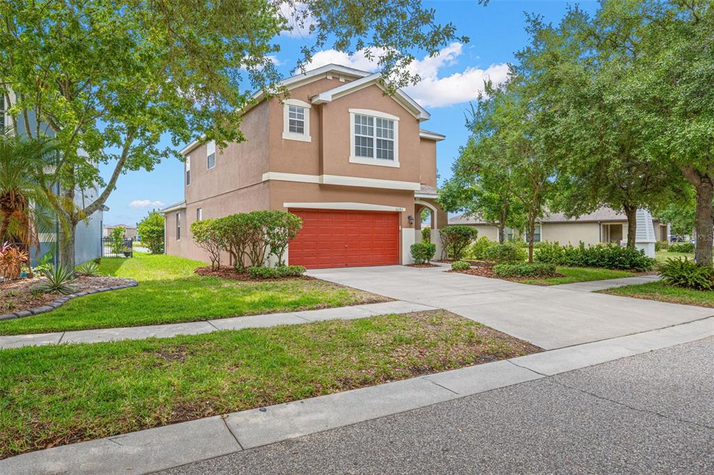 A two-story tan house with a red garage door and a concrete driveway — 10284 NEWMINSTER LOOP, RUSKIN, FL