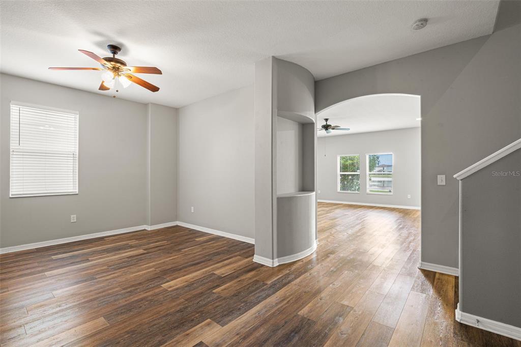 An empty room with wood-look flooring, a ceiling fan, and an arched entryway — 10284 NEWMINSTER LOOP, RUSKIN, FL