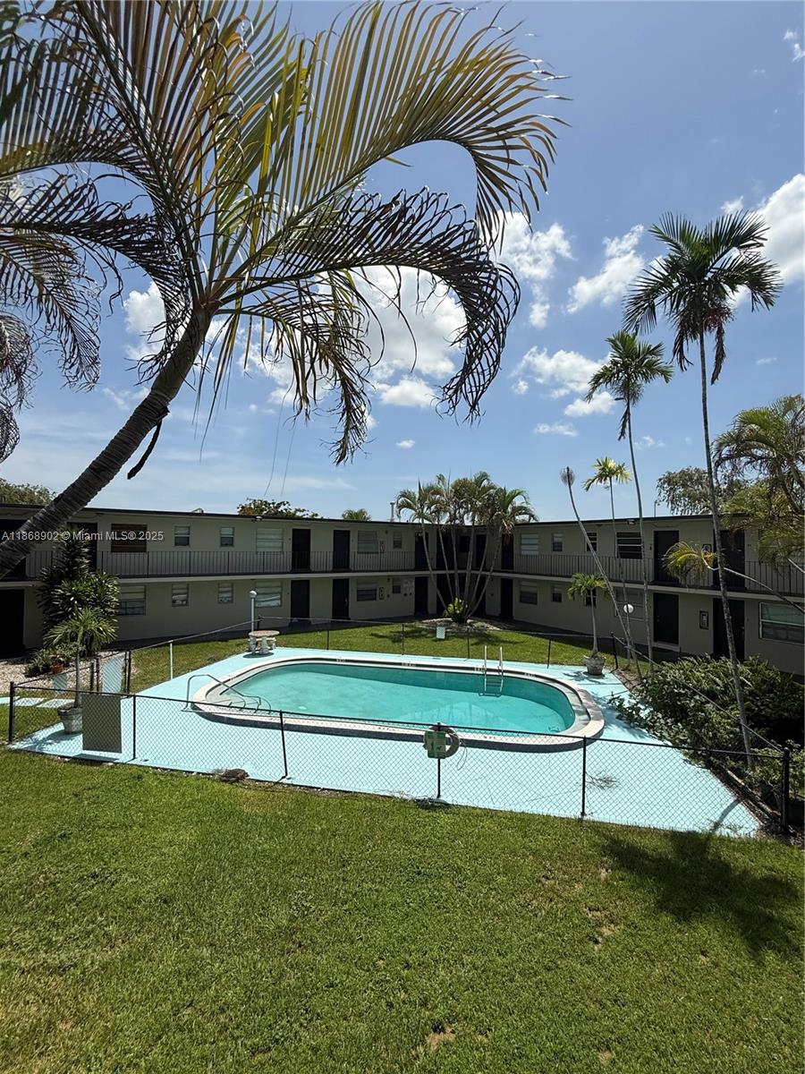 A swimming pool sits in the courtyard of a two-story apartment building with palm trees — 3901 SW 112th Ave # 46, Miami FL 33165, MIAMI, FL