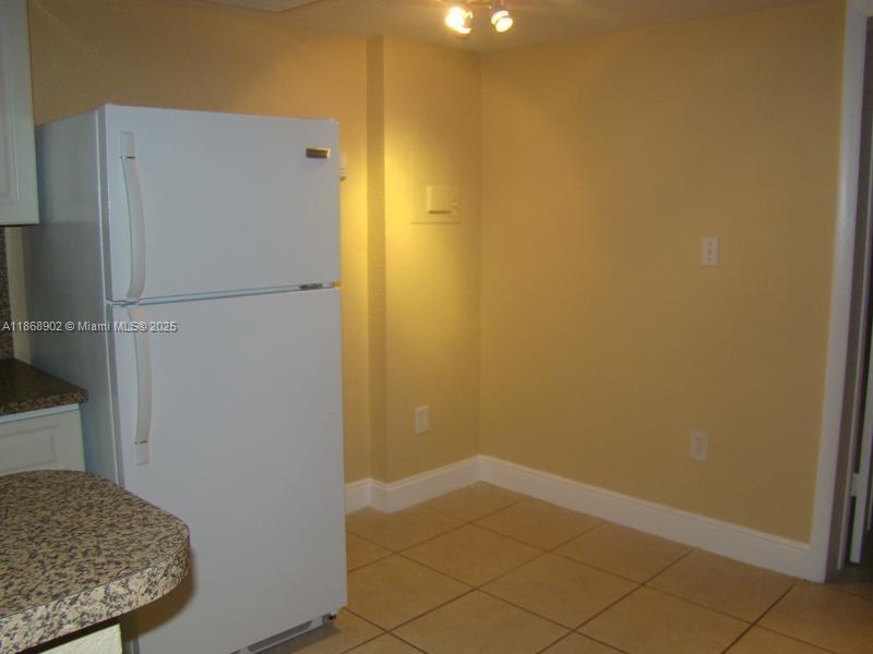 A white refrigerator stands in a kitchen corner with beige walls and tiled flooring — 3901 SW 112th Ave # 46, Miami FL 33165, MIAMI, FL