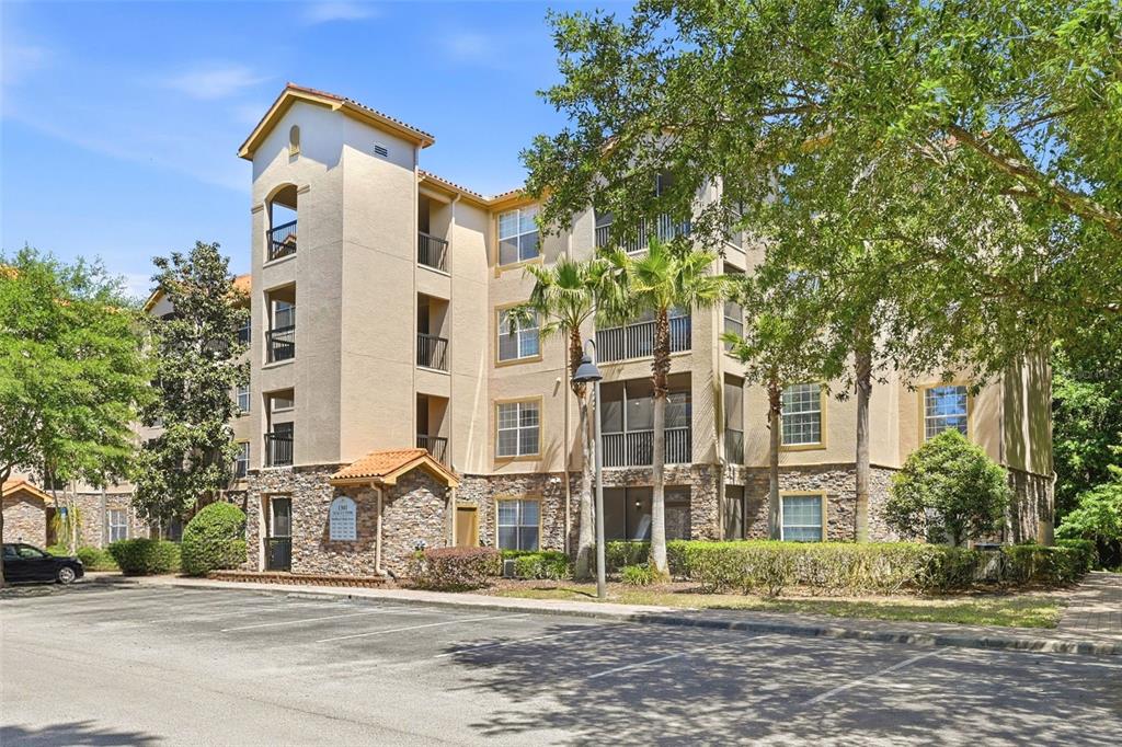 A multi-story apartment building with stucco and stone siding, balconies, and a parking lot — 1301 TUSCAN TERRACE UNIT 9406, DAVENPORT, FL