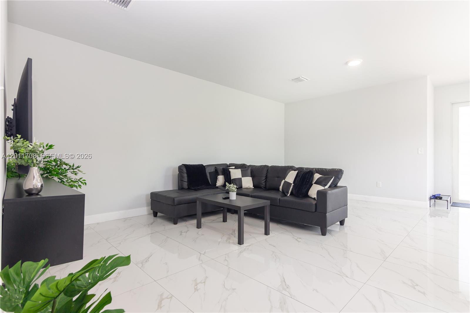 A living room features a black sectional sofa, a coffee table, and white marble flooring — 1968 NW 25th Ave # 1968, Miami FL 33125, MIAMI, FL