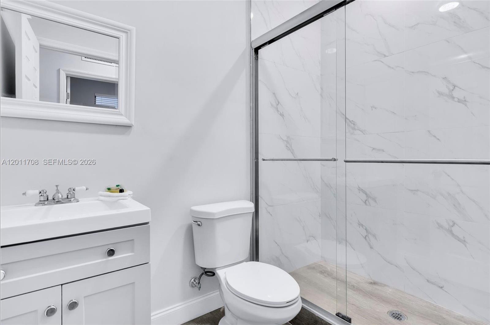 A bathroom features a white vanity, a toilet, and a glass-enclosed shower with marble-look tiles — 1968 NW 25th Ave # 1968, Miami FL 33125, MIAMI, FL