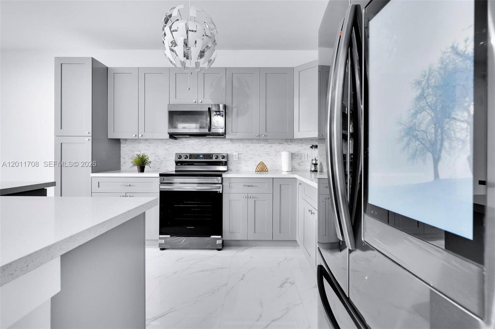 A modern kitchen features gray shaker cabinets, white marble-look countertops, and stainless steel appliances — 1968 NW 25th Ave # 1968, Miami FL 33125, MIAMI, FL