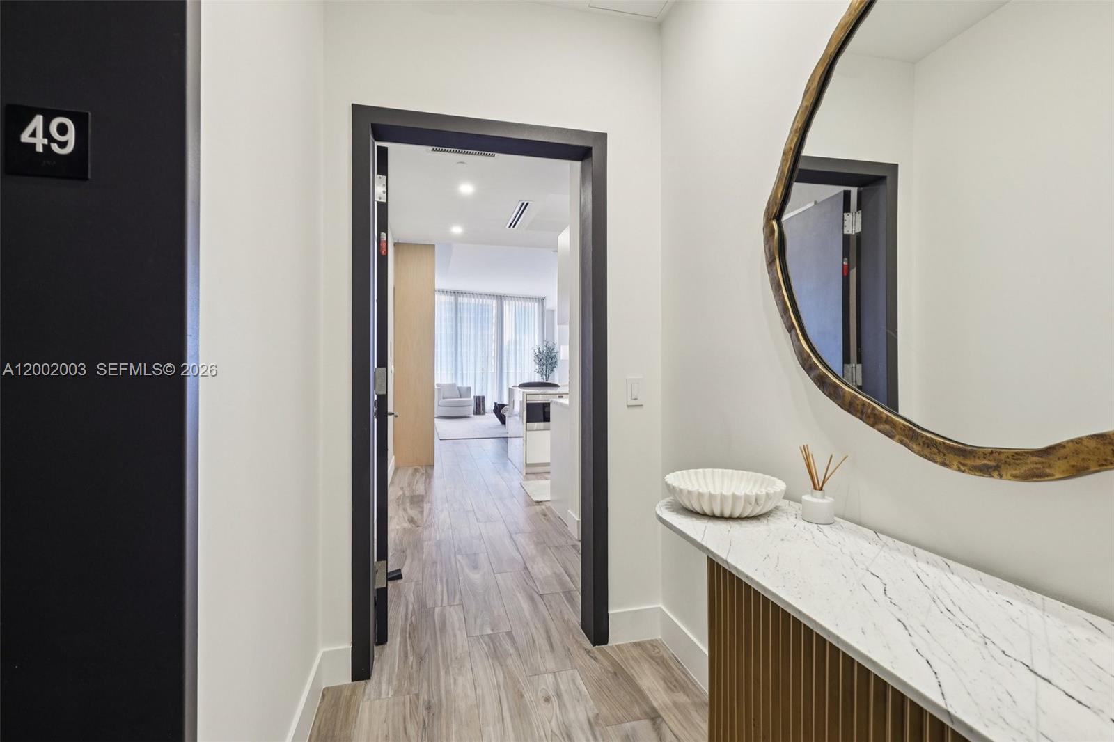 A hallway features a marble console table, a round mirror, and a doorway to a living area — 801 S Miami Ave # 4902, Miami FL 33130, MIAMI, FL