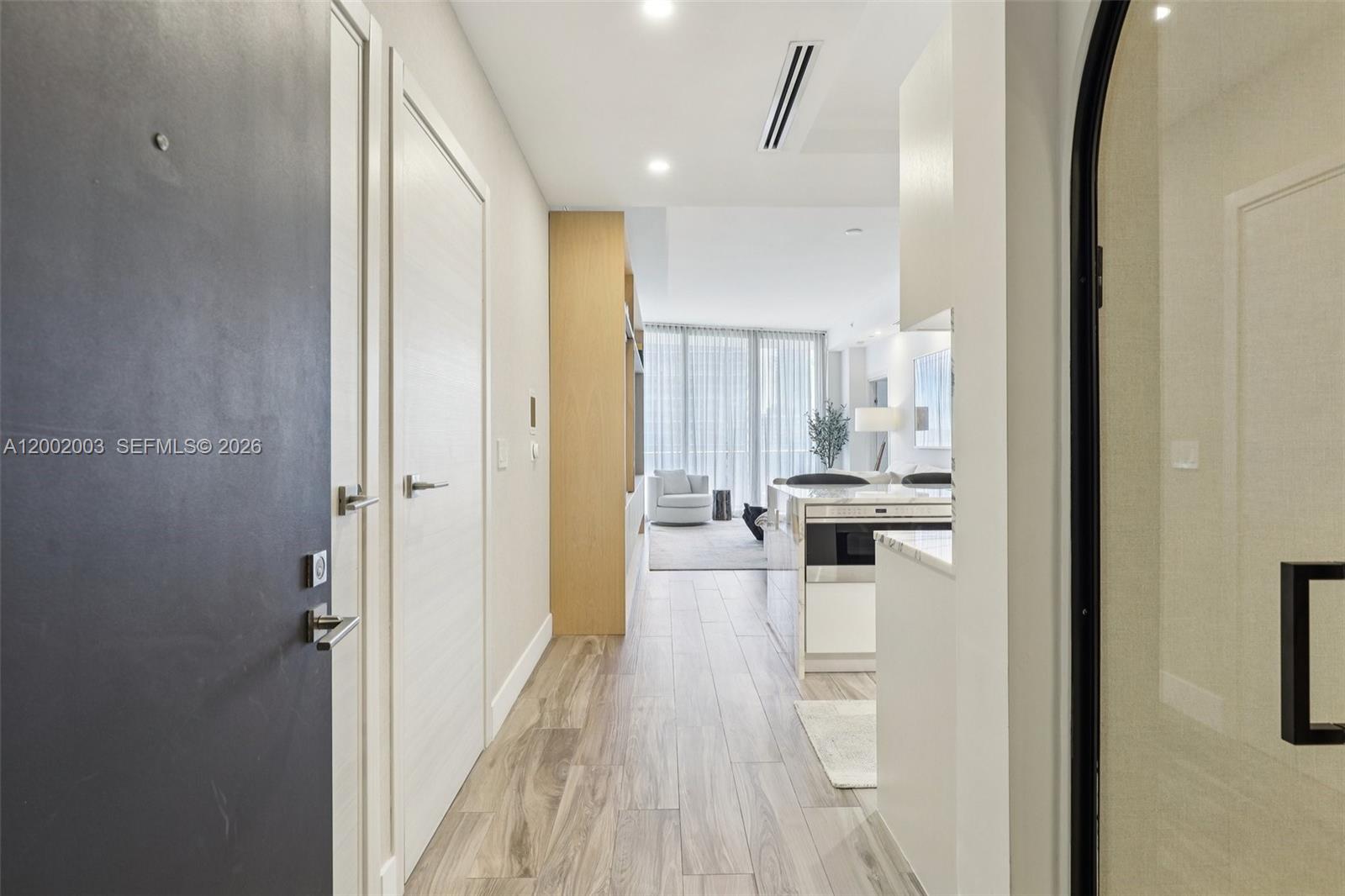 A hallway with wood-look flooring leads into a modern kitchen and living area — 801 S Miami Ave # 4902, Miami FL 33130, MIAMI, FL