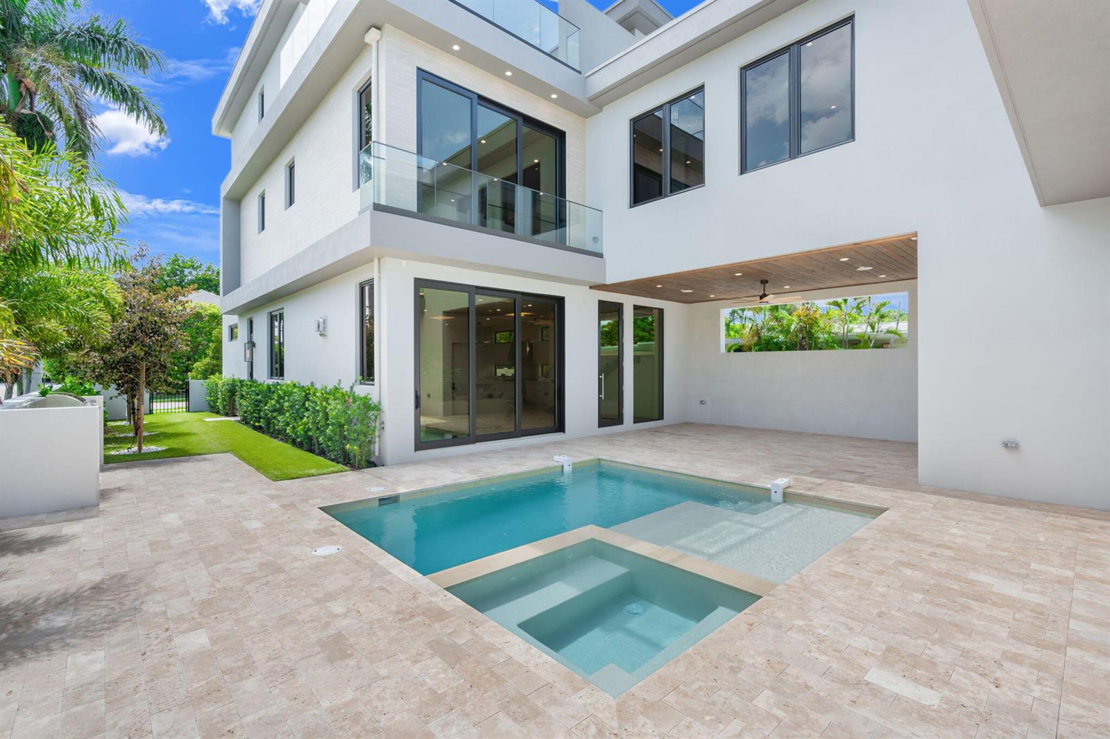 A modern white house features a swimming pool with an integrated spa and stone patio — 301 NE 7th Avenue, Delray Beach FL 33483, DELRAY BEACH, FL