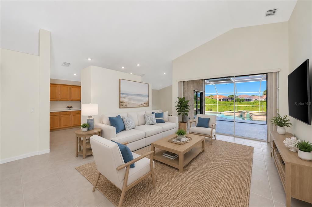 A living room with a vaulted ceiling, neutral furniture, and a sliding door to a pool — 5133 FLAGSTONE DRIVE, SARASOTA, FL