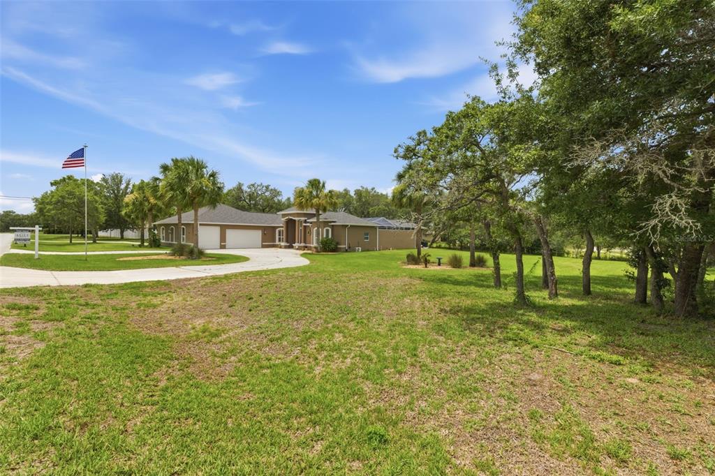 A single-story house with a tan exterior and a circular driveway sits on a lawn — 11145 MOUNTAIN MOCKINGBIRD RD, WEEKI WACHEE, FL