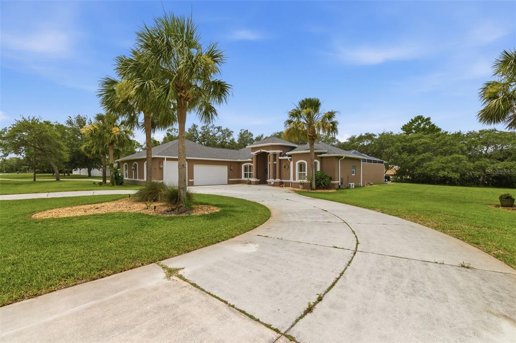 A single-story house with a curved driveway, palm trees, and a multi-car garage — 11145 MOUNTAIN MOCKINGBIRD RD, WEEKI WACHEE, FL
