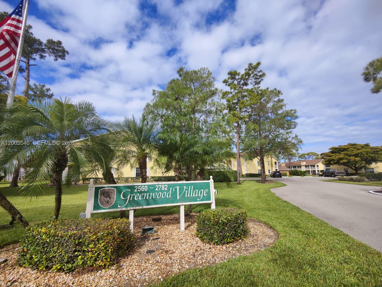 A sign for Greenwood Village stands on a grassy lawn near a paved road — 2668 Kings Lake # 2668, Naples FL 34112, NAPLES, FL