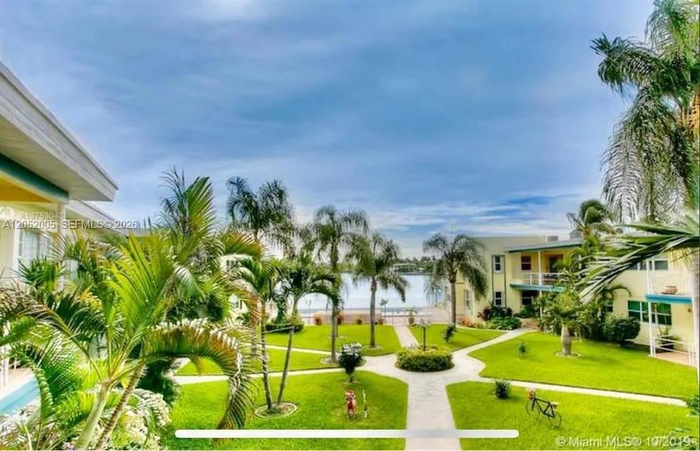 A grassy courtyard with palm trees and walkways sits between two apartment buildings near water — 910 Bay Dr # 9, Miami Beach FL 33141, MIAMI BEACH, FL
