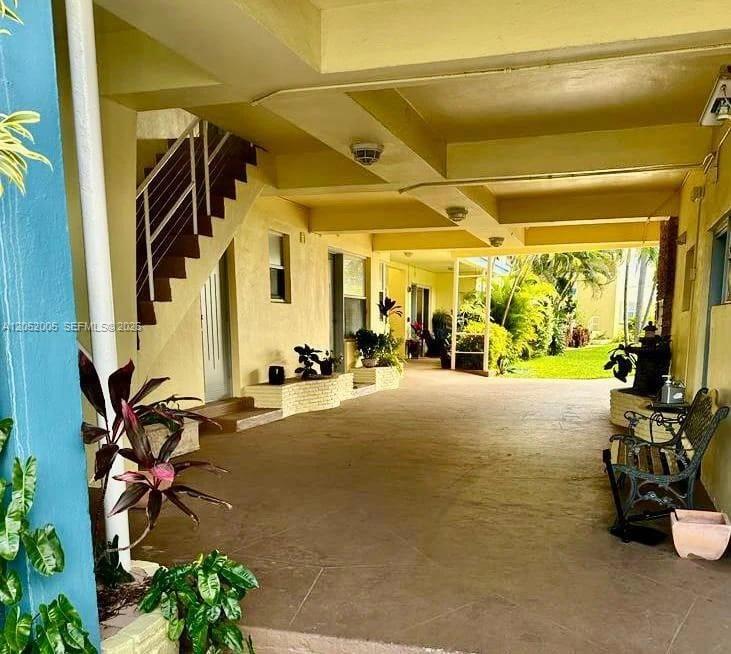 A covered outdoor walkway features a staircase, potted plants, and a bench on a concrete floor — 910 Bay Dr # 9, Miami Beach FL 33141, MIAMI BEACH, FL