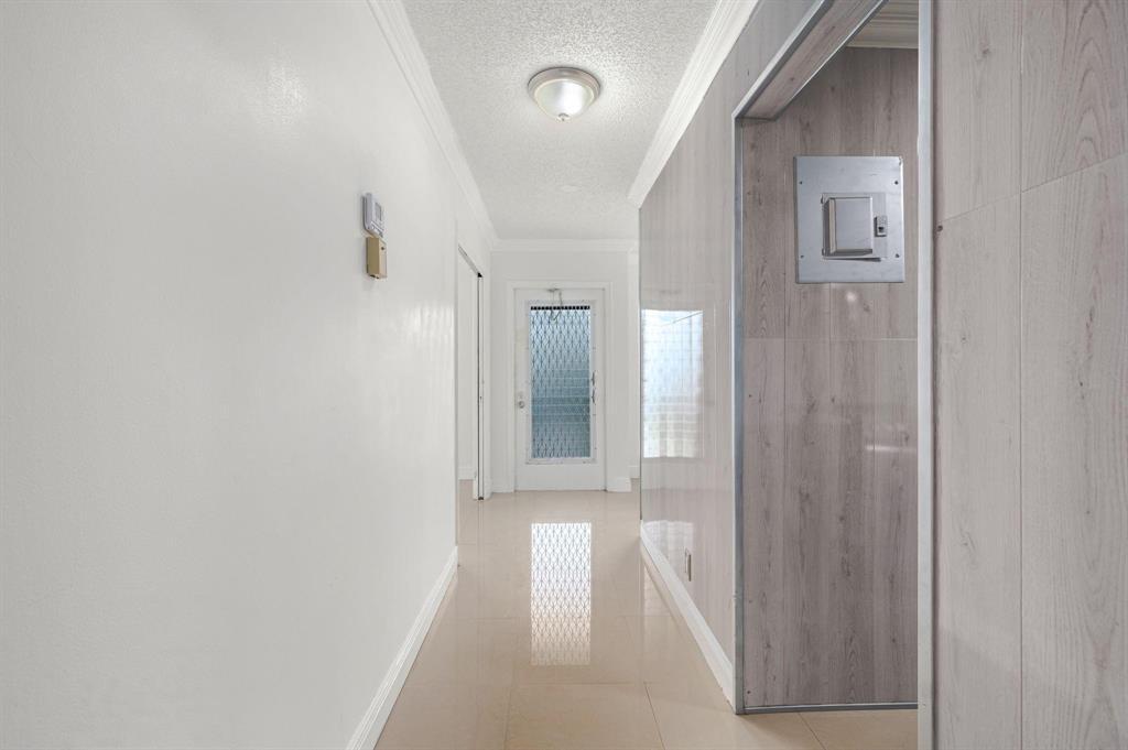 A hallway with white walls, tile flooring, and a door with a decorative glass insert — 2601 Red Hibiscus Boulevard, Delray Beach FL 33445, DELRAY BEACH, FL