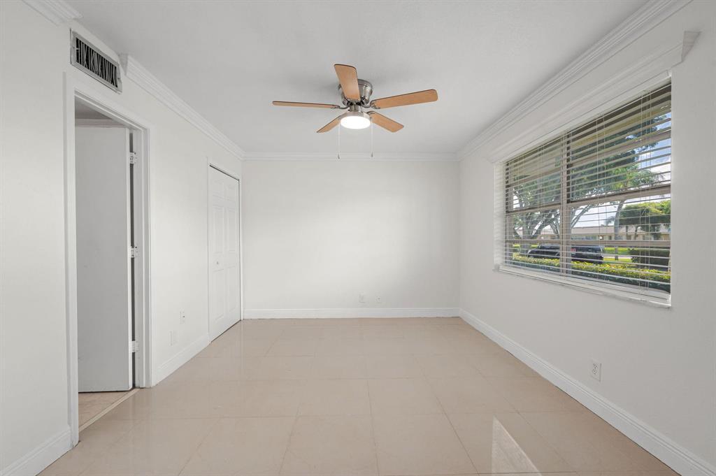 An empty room with white walls, tile flooring, a ceiling fan, and a large window — 2601 Red Hibiscus Boulevard, Delray Beach FL 33445, DELRAY BEACH, FL