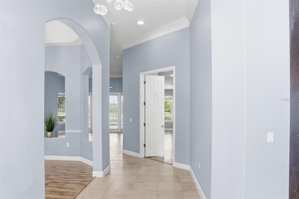 A tiled hallway with light blue walls leads to an open room with wood flooring — 1771 LEE JANZEN DRIVE, KISSIMMEE, FL