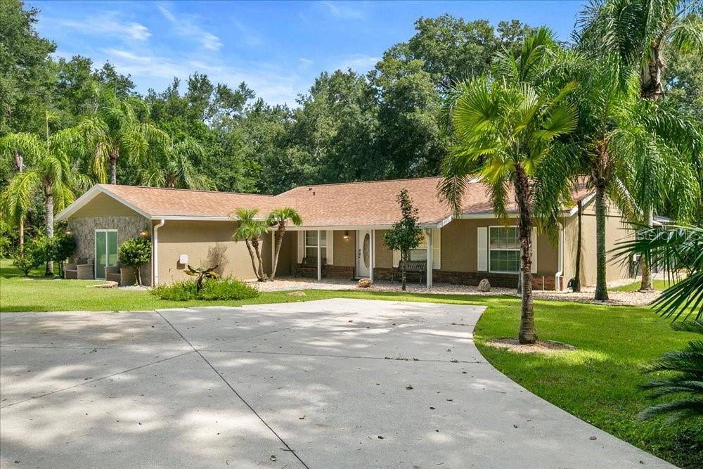 A single-story house with a tan exterior, stone accents, and a concrete driveway — 2619 W PONKAN ROAD, APOPKA, FL