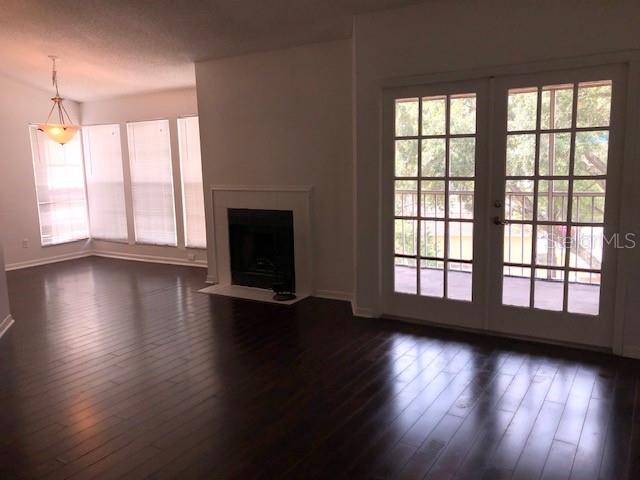 A living room features dark hardwood floors, a fireplace, and glass doors leading to a balcony — 670 SANDY NECK LANE UNIT 202, ALTAMONTE SPRINGS, FL