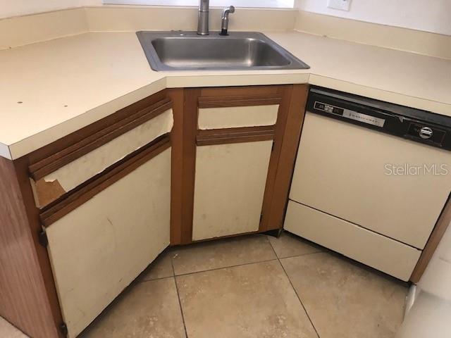A kitchen corner features a stainless steel sink, worn cabinets, and a white dishwasher — 670 SANDY NECK LANE UNIT 202, ALTAMONTE SPRINGS, FL
