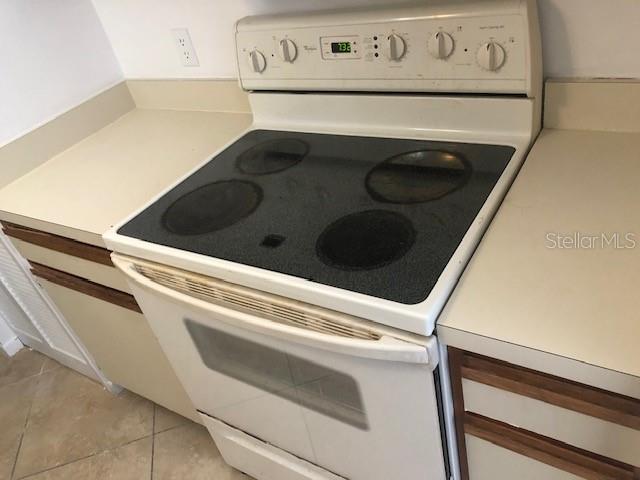 A white electric range with a black glass cooktop sits between beige kitchen countertops — 670 SANDY NECK LANE UNIT 202, ALTAMONTE SPRINGS, FL