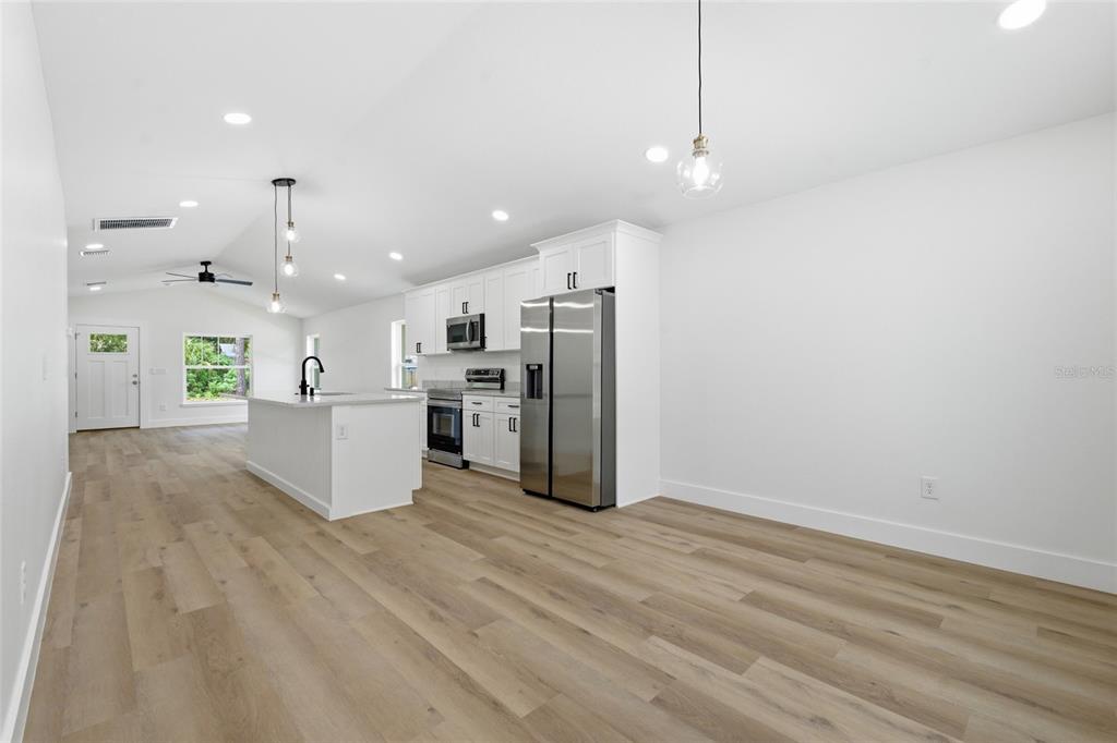 A modern kitchen with white cabinets, stainless steel appliances, and an island on wood flooring — 3837 44TH AVENUE N, ST PETERSBURG, FL