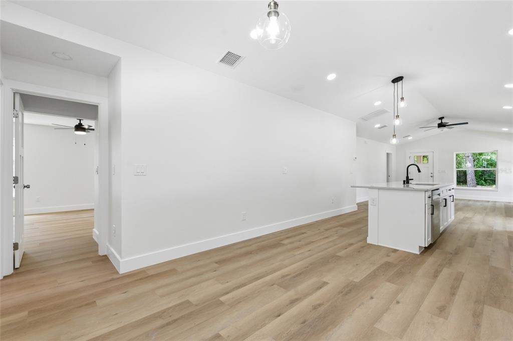 A bright, open-concept kitchen and living area features light wood flooring and white cabinetry — 3837 44TH AVENUE N, ST PETERSBURG, FL