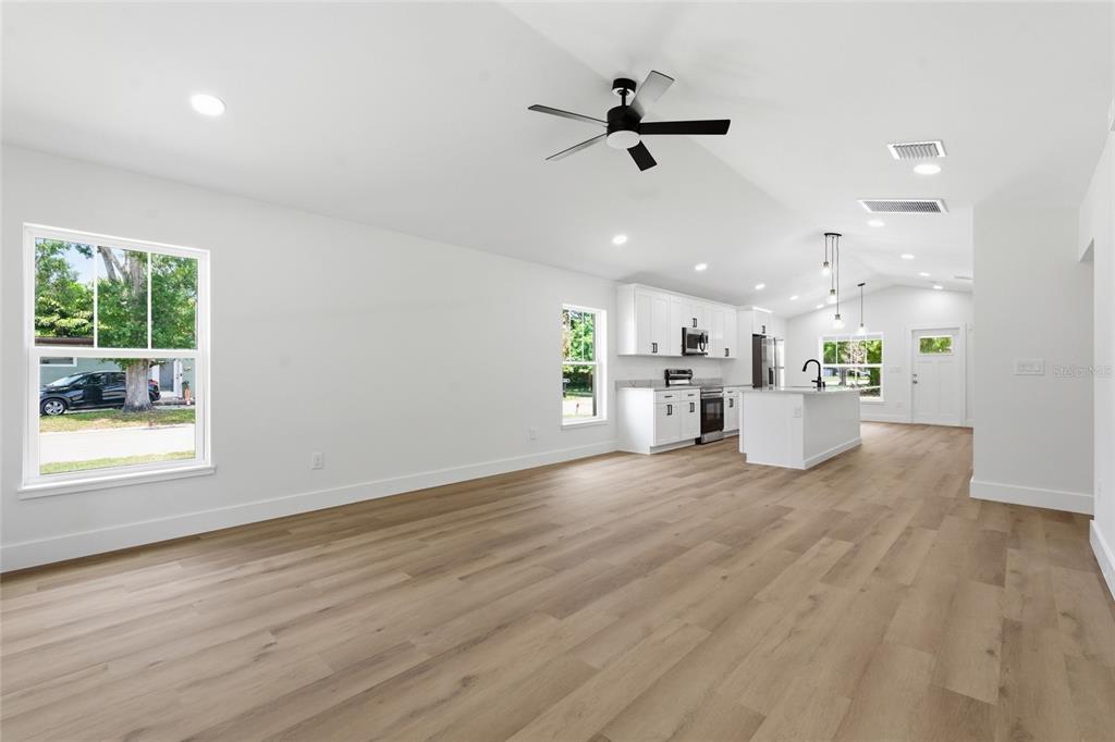An open-concept living area features white walls, light wood flooring, and a modern kitchen — 3837 44TH AVENUE N, ST PETERSBURG, FL