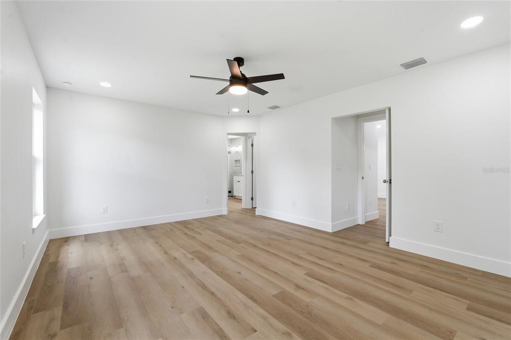 A bright, empty bedroom features white walls, light wood-look flooring, and a ceiling fan — 3837 44TH AVENUE N, ST PETERSBURG, FL