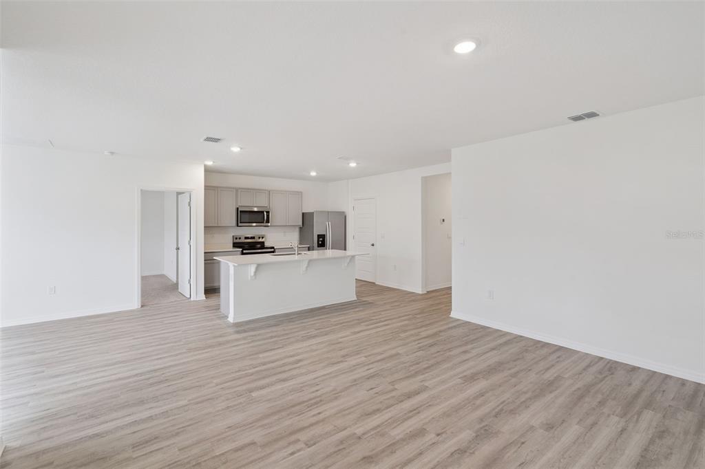 An open-concept kitchen with a white island and light wood-look flooring in a living area — 4973 KATRINA DRIVE, HAINES CITY, FL