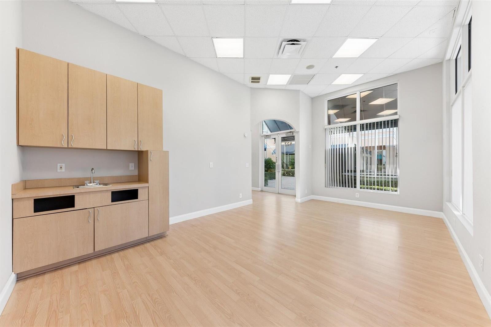 An office space features light wood flooring, light-colored cabinetry with a sink, and large windows — 826 N Dixie Highway # 15, Lantana FL 33462, LANTANA, FL