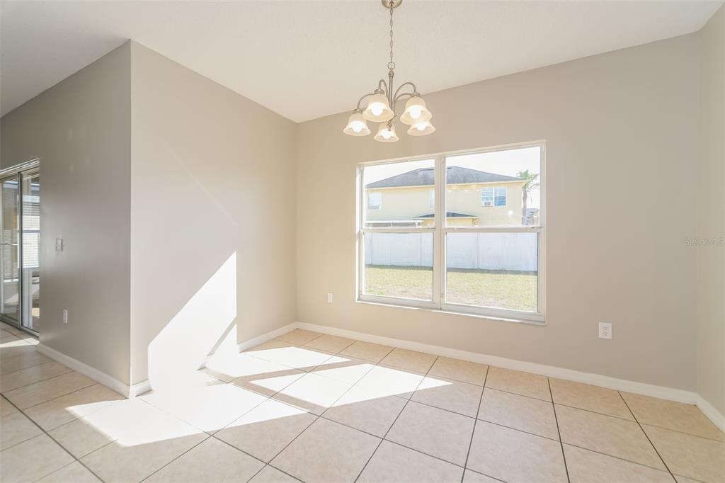 A dining area with beige tile floors, a chandelier, and a large window — 4417 CANOPY COURT, KISSIMMEE, FL